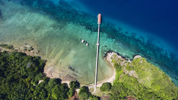 Vista superior foto aérea de avião de uma ilha natureza paisagem com plantas tropicais perto do mar com ondas calmas e molhe . — Fotografia de Stock