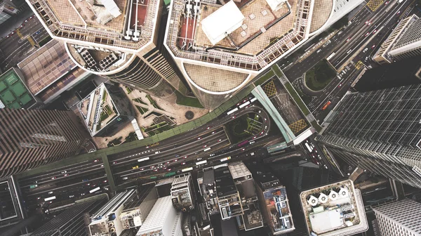 Top προβολή εναέρια φωτογραφία από ιπτάμενους κηφήνες ενός ψηλό ουρανοξύστη με σύγχρονο σχεδιασμό, δρόμο με αυτοκίνητα. — Φωτογραφία Αρχείου