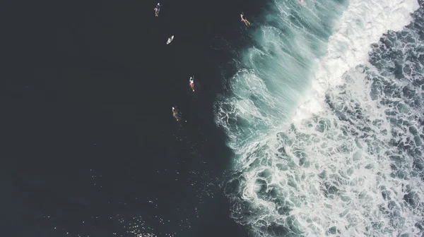Vista dall'alto dall'altitudine del gruppo i surfisti stanno nuotando su tavole da surf in mare dopo la grande onda che si rompe sulla bellissima costa . — Foto Stock