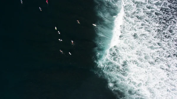 Вид сверху с дрона группы серферов, стремящихся в океан, чтобы поймать очередную красивую волну во время уроков серфинга в школе Бали — стоковое фото