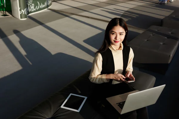 Asiatica donna d'affari è seduto in interni moderni vicino touch pad con schermo vuoto — Foto Stock