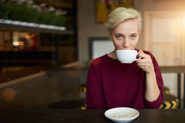 Hipster chica con corte de pelo corto de moda vestido con suéter beber café para el desayuno —  Fotos de Stock