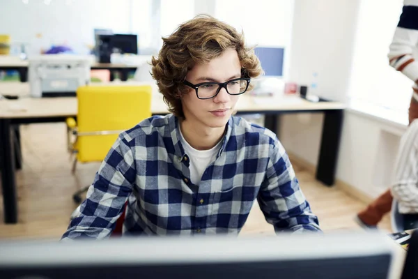 IT programmer in trendy eyewear coding software application for university exam — Stock Photo, Image