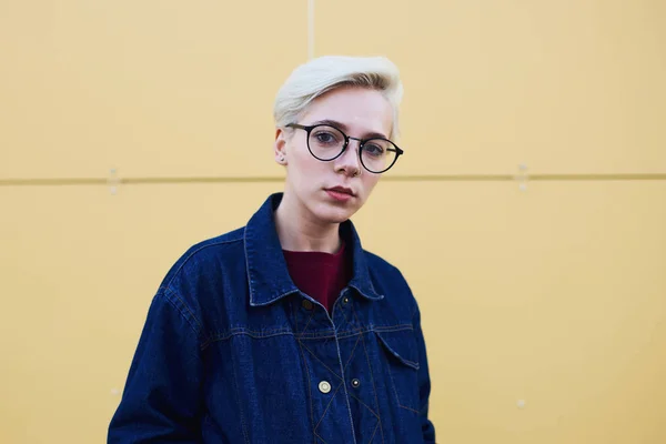 Mädchen-Hipster mit trendiger Brille blickt in die Kamera, die auf städtischen Straßen steht — Stockfoto