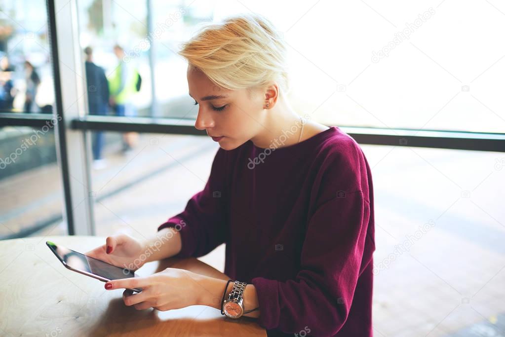 Hipster girl using modern touchpad and wifi to internet in cafe copy space for your advertising