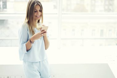 Alan coworking içinde kablosuz bağlantı kullanarak smartphone ile birlikte çalışan kız