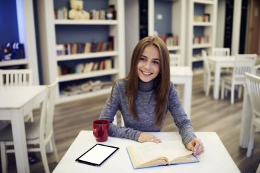 Ücretsiz Wi-Fi bölgesi dersler başlamadan önce kahvaltı için sıcak kahve içme ile Üniversite Kütüphanesi masada oturan güzel kadın