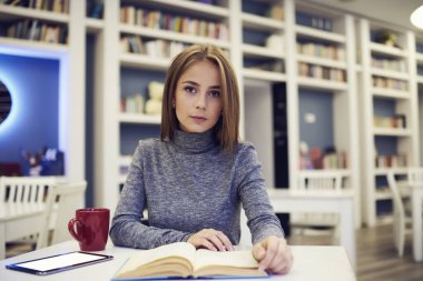 Öğrenci tablet ile boş perde ile çoklu ortam içeriğini coworking oturan kız rereading roman oluşturma