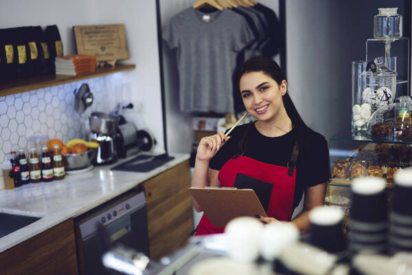 Barista in apron checking documentation