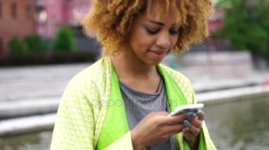 Çekici afro Amerikan hippi kız açık havada duran sırasında smartphone uygulamaya arkadaşlarınızla sohbet