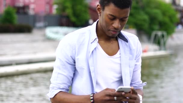 Varón joven de piel oscura que usa conexión a Internet en un dispositivo de teléfono móvil — Vídeo de stock