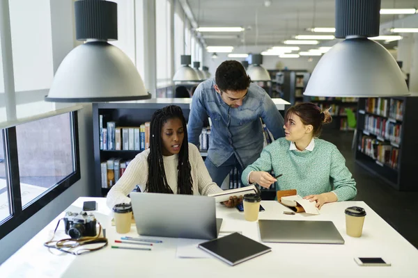 Grupo de estudiantes que se preparan para los exámenes en la biblioteca universal — Foto de Stock