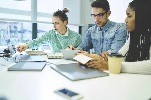 Studenti maschi e femmine che fanno i compiti insieme in biblioteca — Foto Stock