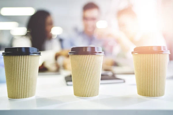 Craft paper cup of coffee to go with coworkers on background — Stock Photo, Image