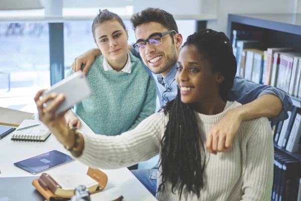 Internationale studenten selfie maken tijdens het werken op project samen in bibliotheek — Stockfoto