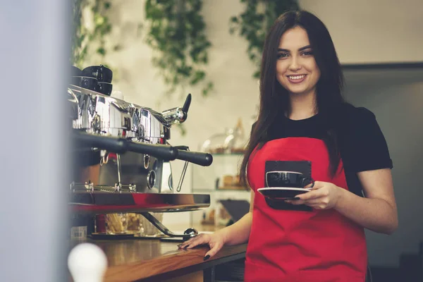 Весела офіціантка насолоджується робочим днем у кафетерії, роблячи каву аромату за допомогою обладнання — стокове фото