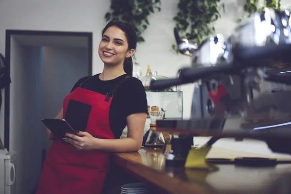 Portret kobiet barista uśmiechając się do kamery trzymając kubek kawy — Zdjęcie stockowe