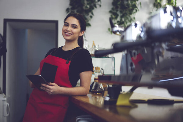 Portrait of female barista smiling to the camera holding cup of coffee