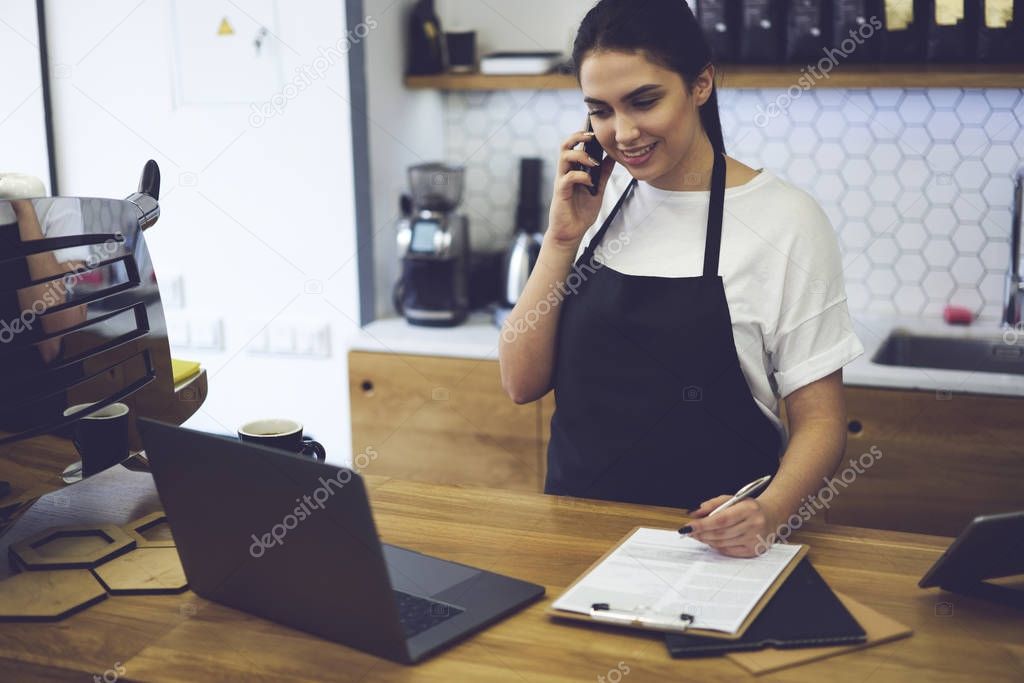 Smiling barista standing at bar and talking with web consultant about ordering food for cafeteria