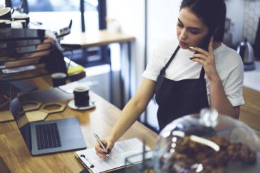 Veritabanından, Restoran girişimci accountings kontrol etmek için dizüstü bilgisayar kullanarak kadın kahve ev sahibi