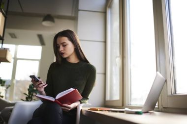 Bölge coworking beyaz öğrenci ile modern bilgisayar oturan ve okuma kitapları