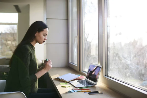 Slimme hipster meisje zit in de ruimte tijdens het zoeken van informatie uit verschillende bronnen coworking — Stockfoto