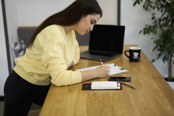 Caucasian concentrated model dressed in casual outfit writing CV for searching new job — Stock Photo, Image