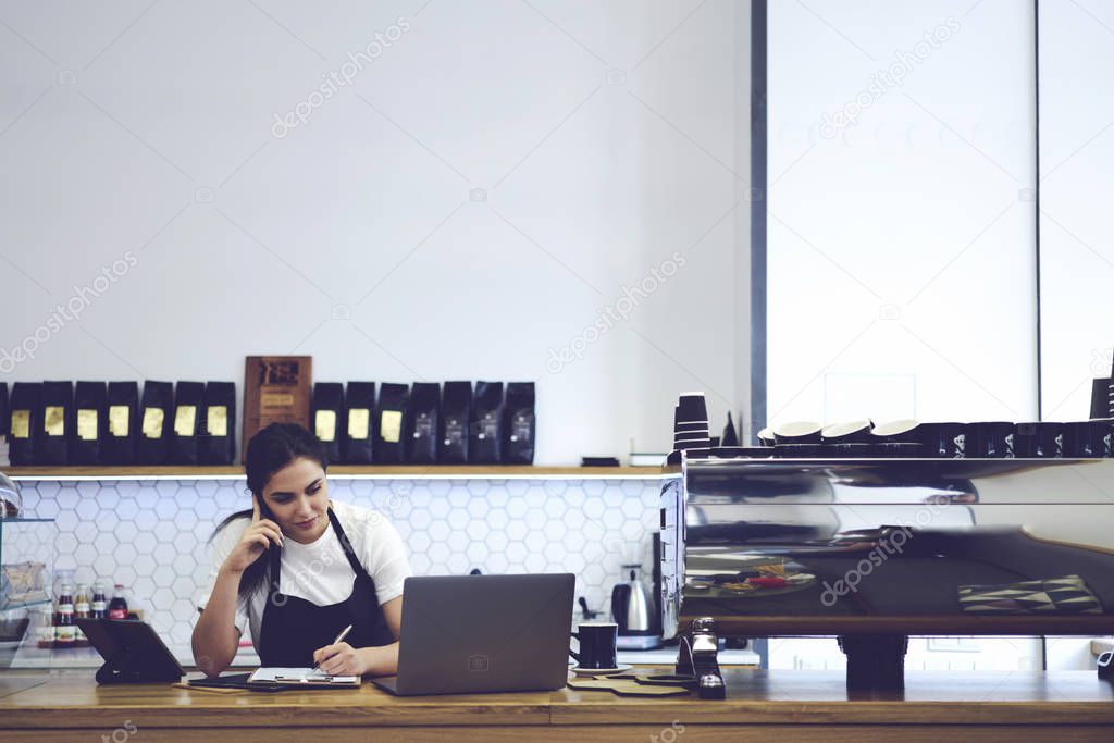 Female coffee shop cashier standing against copy space wall