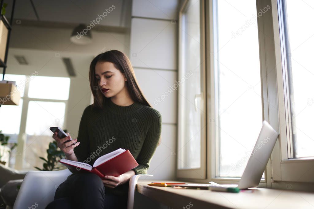 Caucasian student sitting with modern computer and reading books in coworking zone