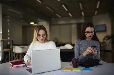 Kadın meslektaşları sosyal ağlarda arkadaşlarınızla sohbet ederken modern cihazlar kullanarak coworking