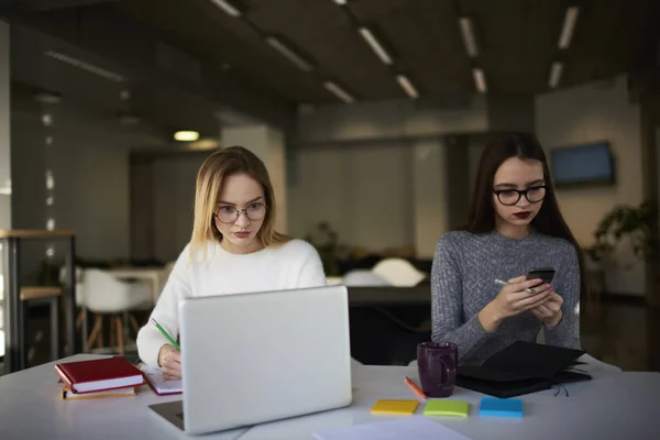 Coworking female colleagues using modern devices while chatting in social network with friends — Stock Photo, Image