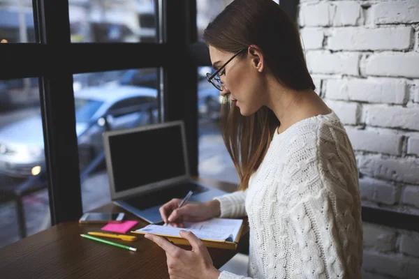 Young freelancer planning work on week writing down all details of organization issues in notebook — Stock Photo, Image