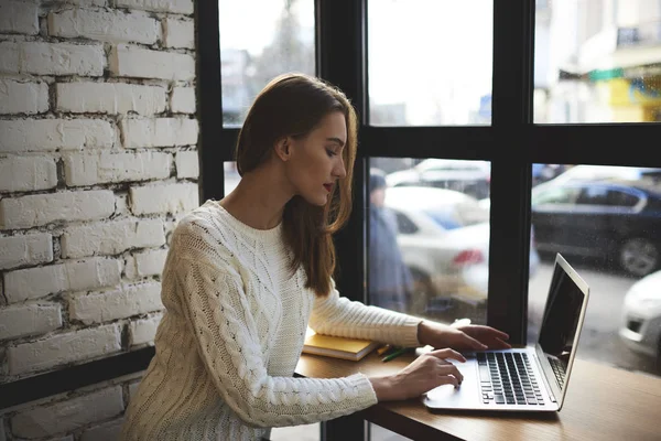 Lindo usuário de internet do sexo feminino digitando informações no teclado em busca de conexão com wireless — Fotografia de Stock