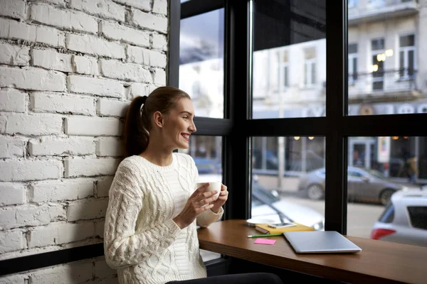 Щаслива жінка насолоджується хорошим настроєм зі смачною кавою в кафетерії — стокове фото