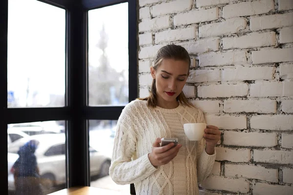 Hipster-Mädchen liest Nachrichten, die in der Nähe von Ziegelmauer stehen — Stockfoto