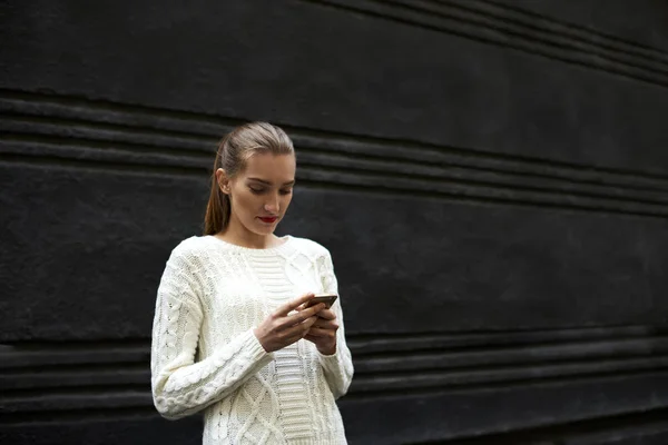 Hipster-jente som bruker smarttelefon med 4G-internett mens hun står i nærheten av salgsbakgrunnen for annonsen din – stockfoto
