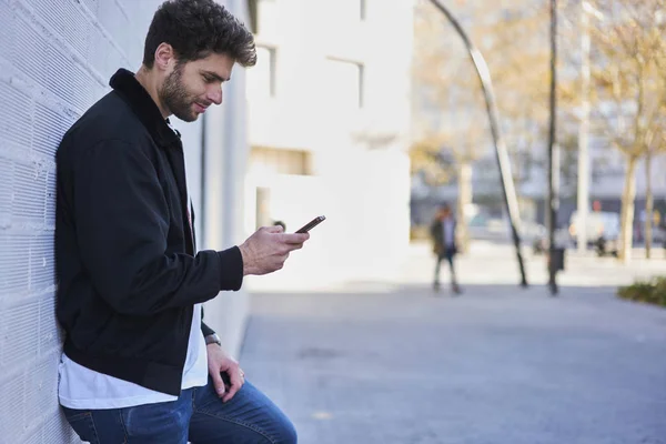 Junge männliche Bloggerin konzentriert sich darauf, Kommentare unter Reisevideos auf dem Smartphone zu lesen — Stockfoto