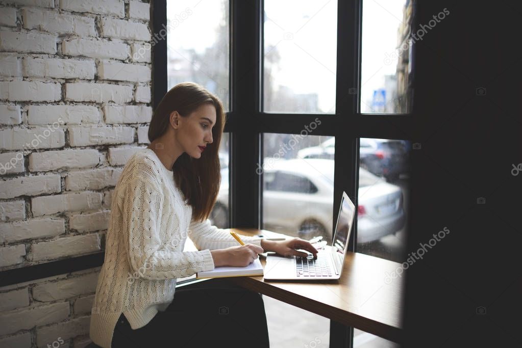 Smart gorgeous young woman studying indoors and preparing for exams using modern laptop connecting to wireless