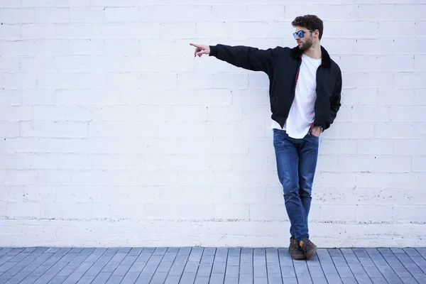 Hipster chico posando en ropa elegante, señalando con el dedo en el espacio de copia — Foto de Stock