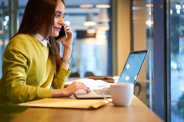 Mujer joven que trabaja en línea usando ordenador portátil con pantalla simulada conectada a Internet inalámbrico gratuito — Foto de Stock