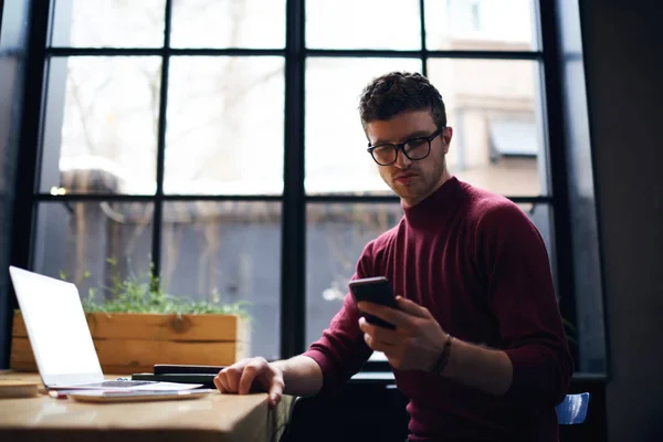 Όμορφος σοβαρή ανδρική freelancer ανάγνωση κειμένου μηνύματα ελέγχου email στην κινητή τηλεφωνία — Φωτογραφία Αρχείου