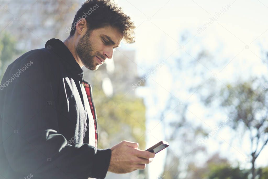 Hipster guy using  modern mobile phone while enjoying good day. Copy space area for your advertising