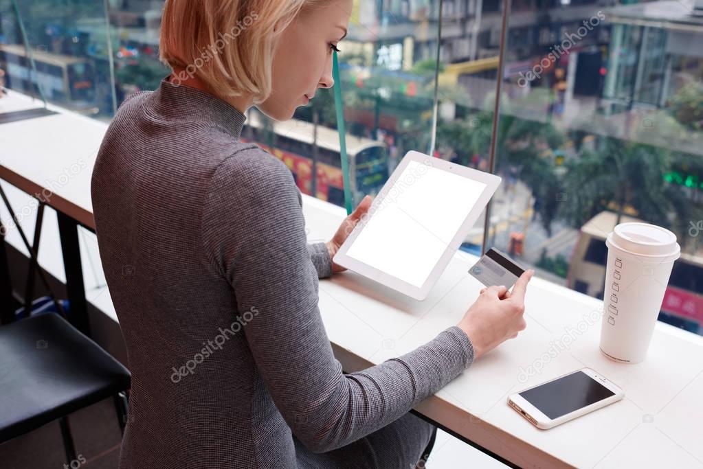 Young female using modern touchpad with mock up screen connected to 4G internet in coffee shop