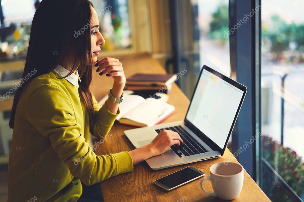 Confident copywriter concentrated on remote job sitting in modern interior cafe with wifi