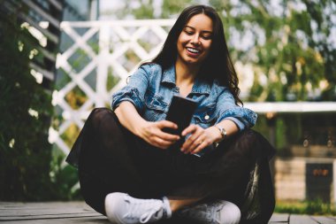 Neşeli genç kadın video sohbet etmek yolu ile lotus pozisyonda oturan smartphone aygıt arkadaşıyla bahsediyoruz. Pozitif hippi kız fotoğrafları cep telefonunda yeni yazı başarılması için yapma