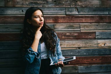 Kıvırcık saç düşünce yeni planları ile düşünceli esmer kadın blogger. Promosyon arka plan üzerinde dijital tablet duran dalgın genç kadınla. Kopyalama alanı alanı reklam için