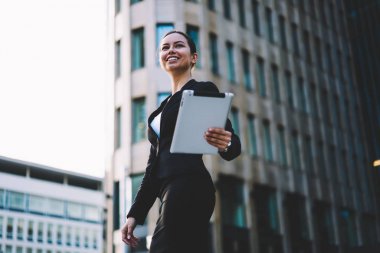 Müreffeh gülümseyen Mali İşler Müdürü dijital tablet cihaz tutan ve modern mimarinin Öğle arasında gezinme şık giyim giymiş. Touch pad açık havada yürüyüş ile başarılı bankacı