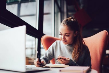 Notlar ve dizüstü bilgisayar ile kafede oturan yaratıcı tasarımcı gülümseyen.