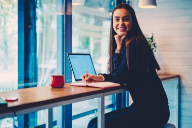 Kafe iç proje yazma öğrenme zaman harcama neşeli esmer öğrenci portresi.