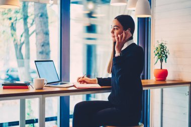 Neşeli kadın yazarı ile telefon görüşmesi sırasında notlar yapma istemci proje ayrıntılarını tartışmak portresi.